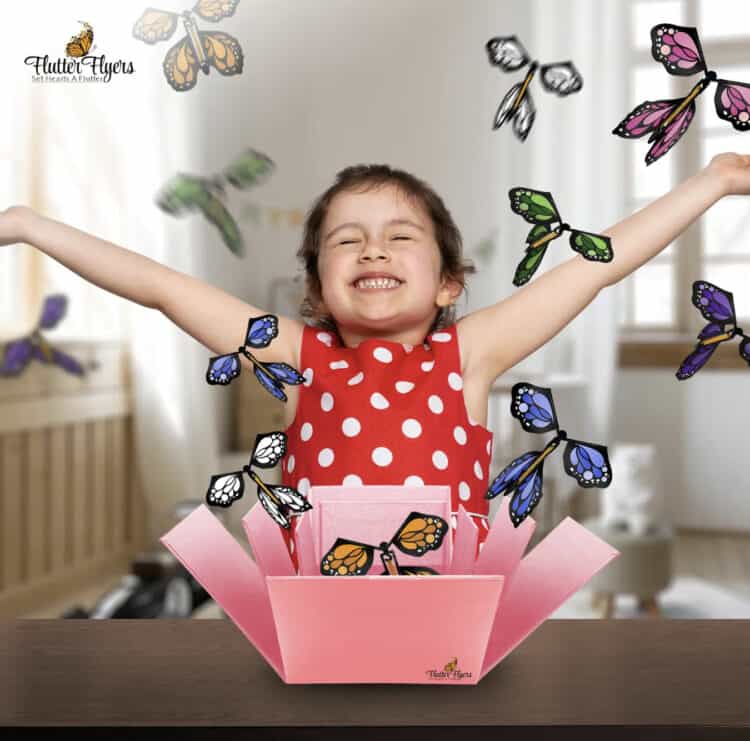 A little girl with hands up as Flutter Flyers fly out of a box.